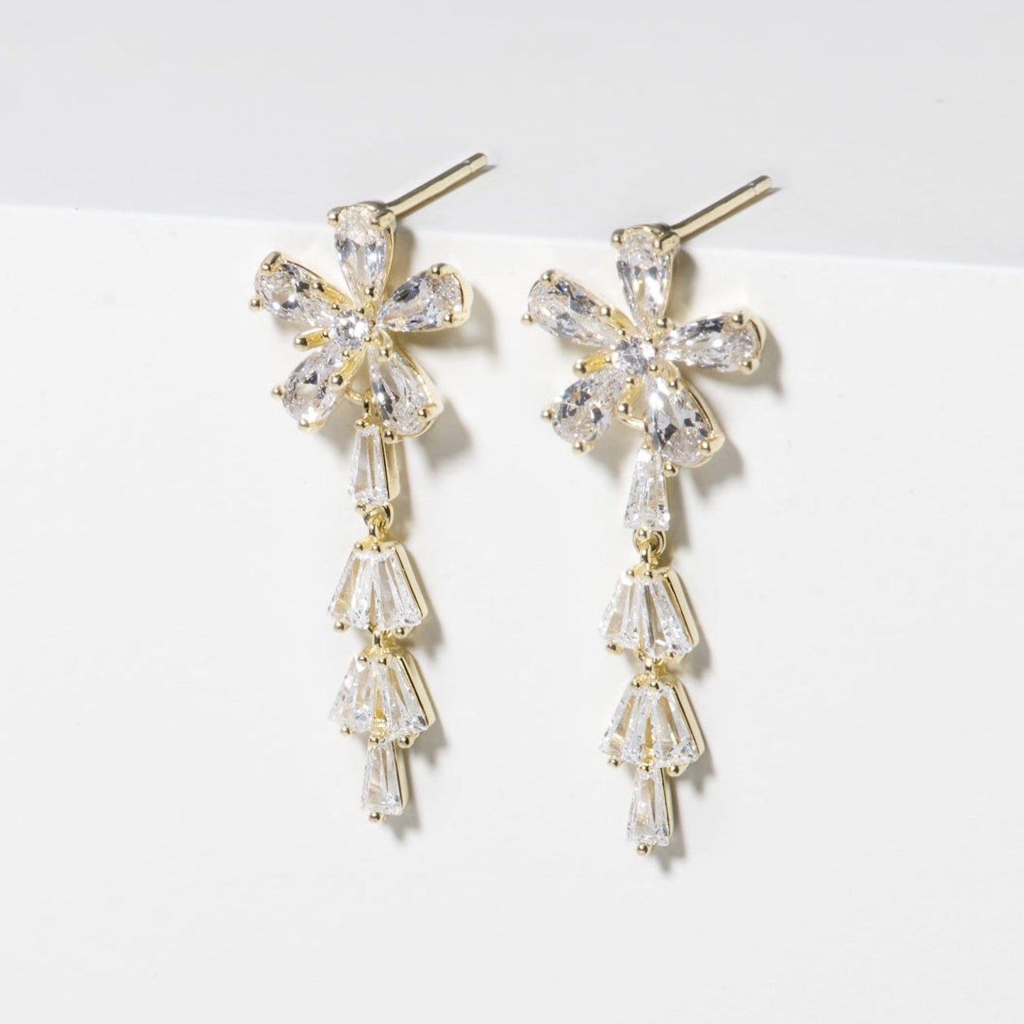 Pair of gold and crystal earrings on a white surface