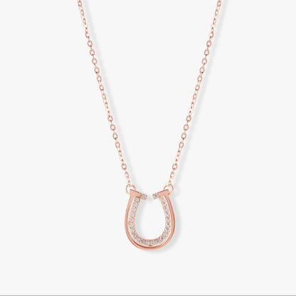 Rose gold horseshoe pendant necklace with pavé stone accents on a fine chain.