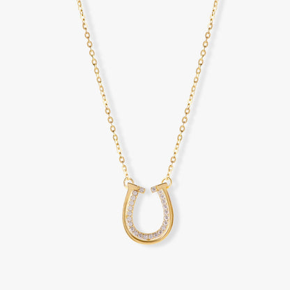 Gold horseshoe pendant necklace with pavé stone accents and a long chain.