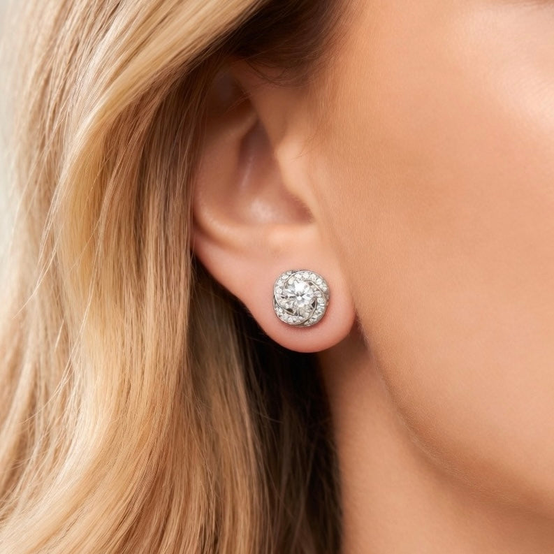 Round moissanite halo stud earrings in love-knot design, worn on ear