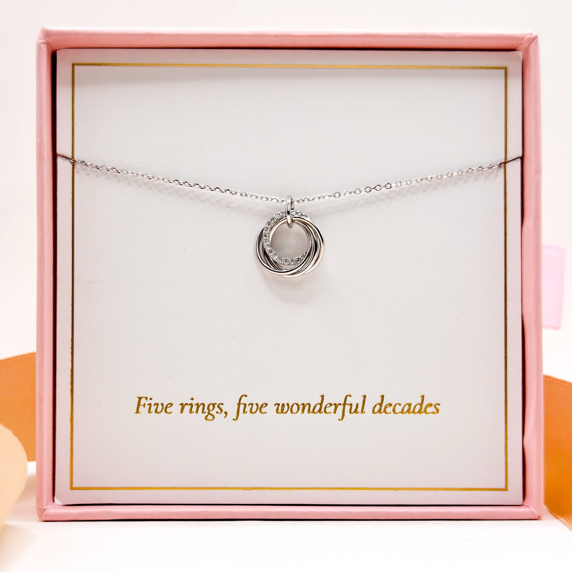 Silver-tone necklace with circular ring pendant displayed on a gift box