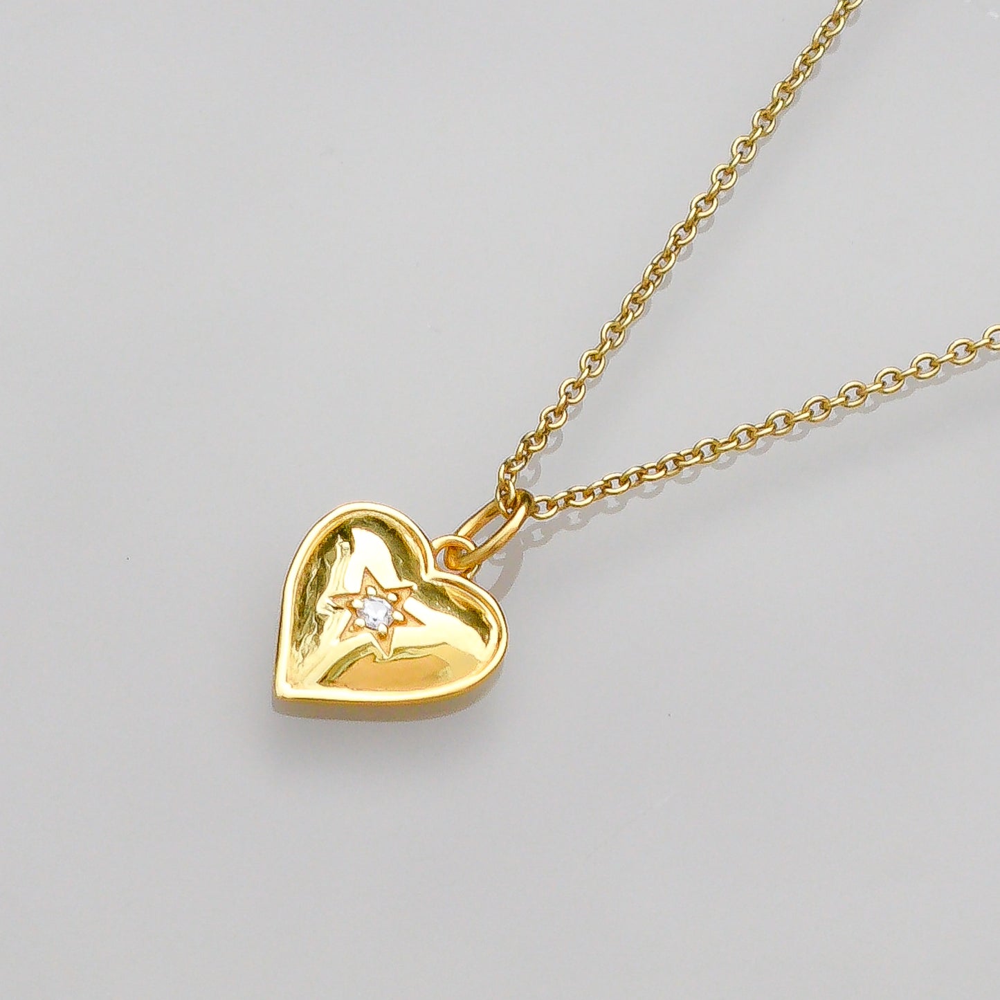 Gold vermeil heart pendant close-up with star detail on gold chain