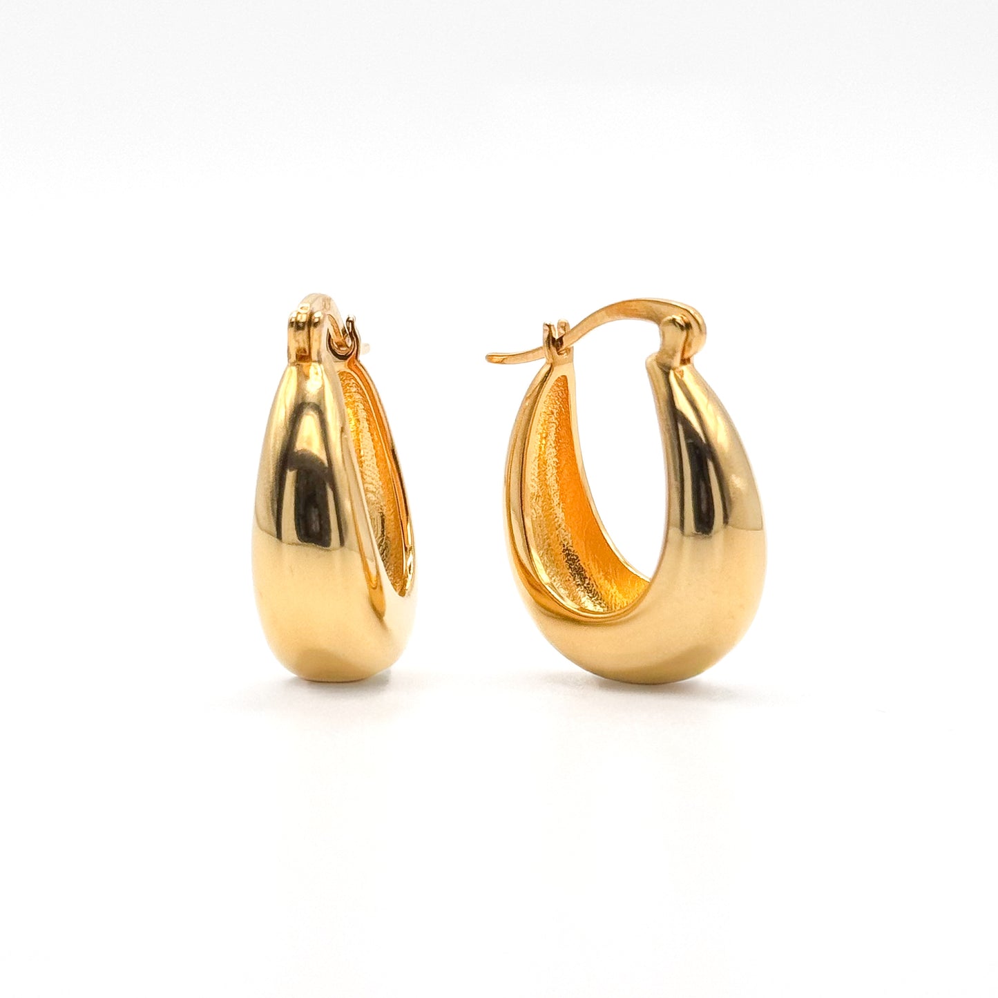 Chunky gold hoop earrings with smooth polished oval shape and hinge clasp