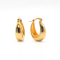 Chunky gold hoop earrings with smooth polished oval shape and hinge clasp
