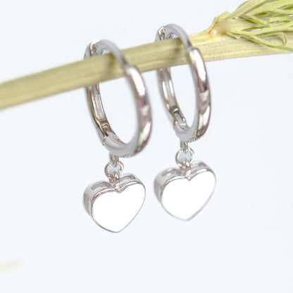 Silver heart huggie earrings close-up, round hoop with heart dangle charm