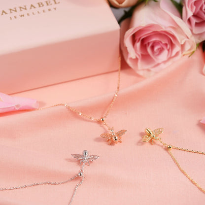 Bee charm necklace set with gold and silver bee pendants on pink fabric