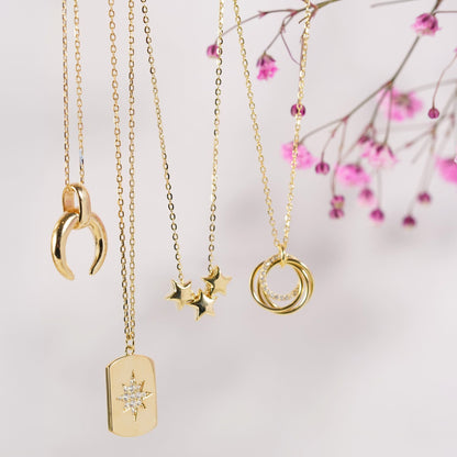 Gold-tone necklace with crescent moon, star, and ring charms on chain