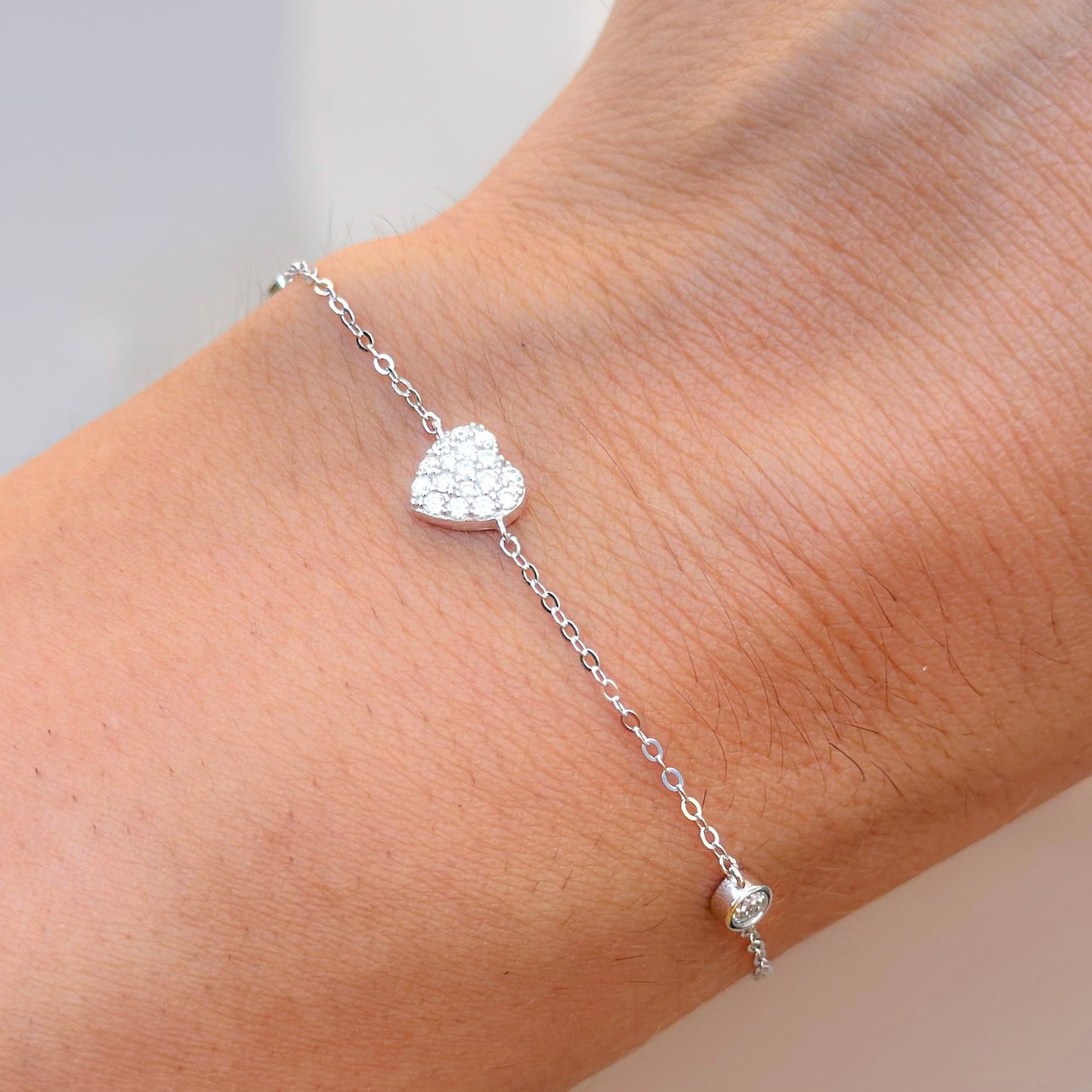 Moissanite diamond heart bracelet with silver chain and pavé heart charm on wrist