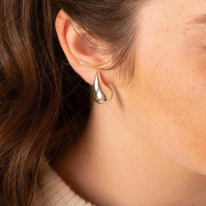 Polished silver teardrop statement earring with pointed top shown on ear