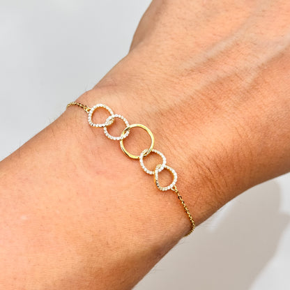 Gold-tone bracelet on wrist with five round ring links and sparkle accents