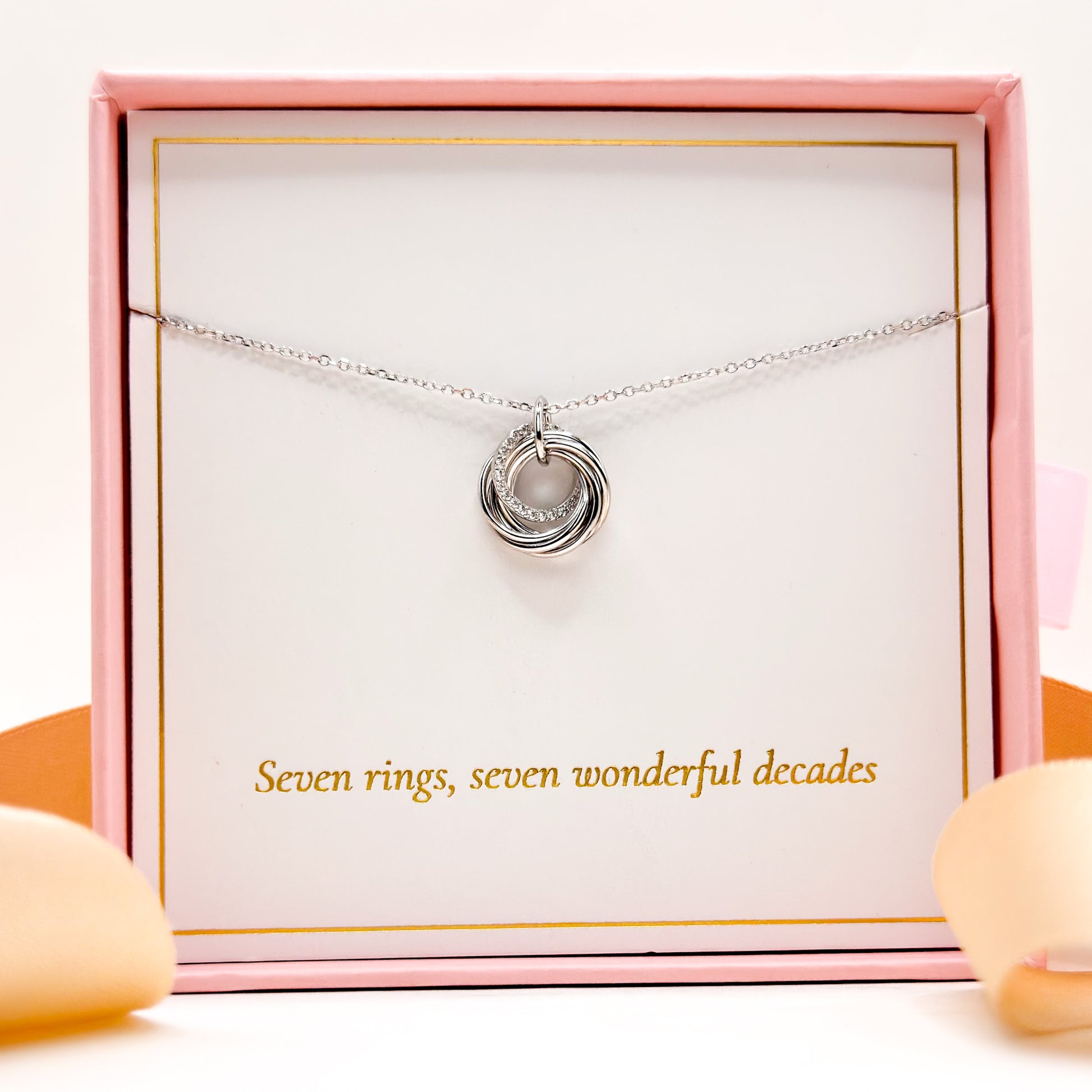 Silver 70th birthday necklace with round 7-ring pendant laid in a gift box