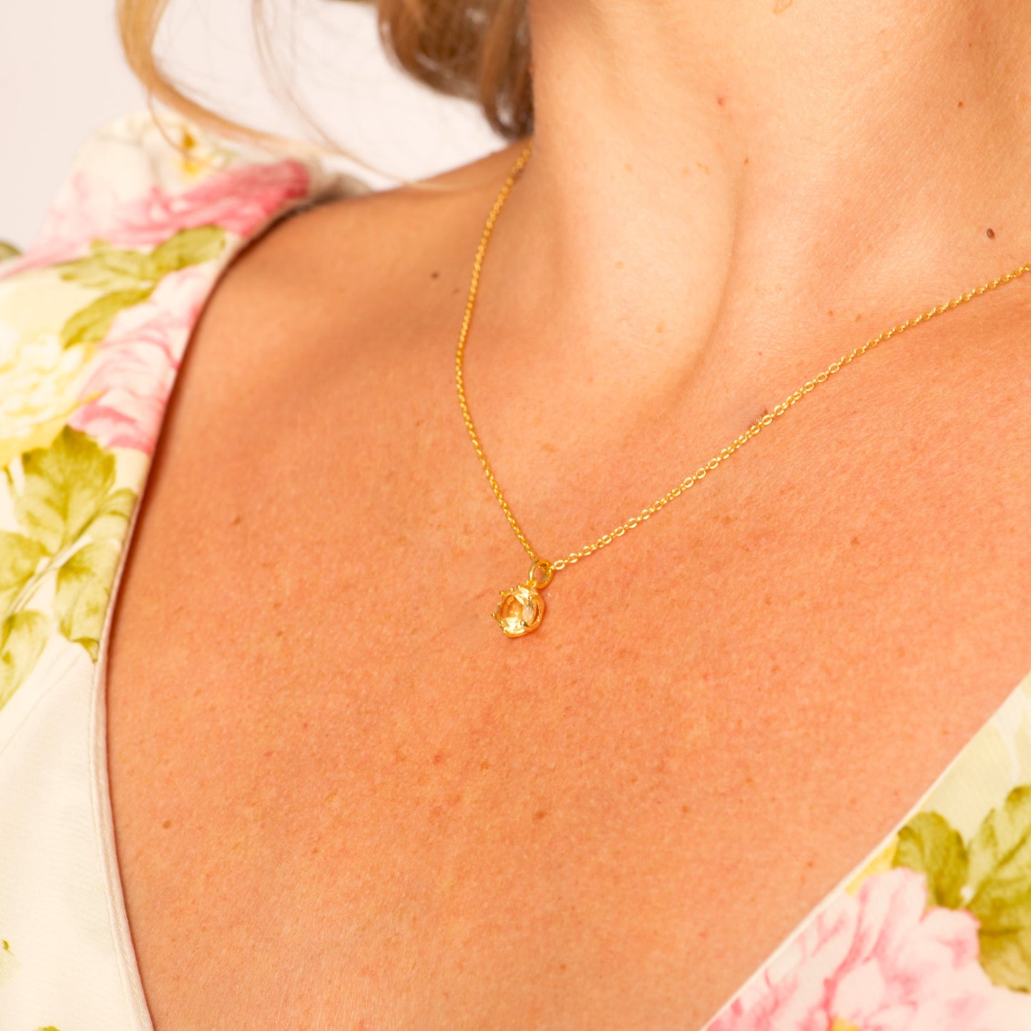 Gold-tone chain necklace with round citrine gemstone pendant at the collar