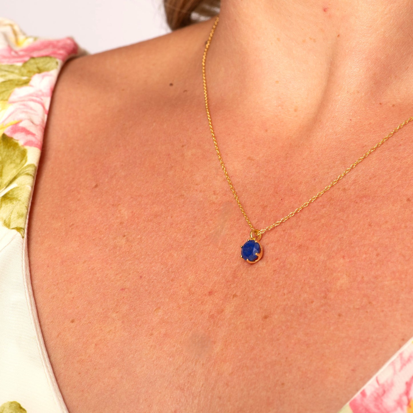 Gold-tone necklace with small round blue lapis stone pendant on chain