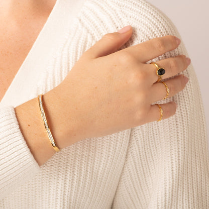 Gold crystal bangle cuff on wrist, hinged design with clear stones in a line