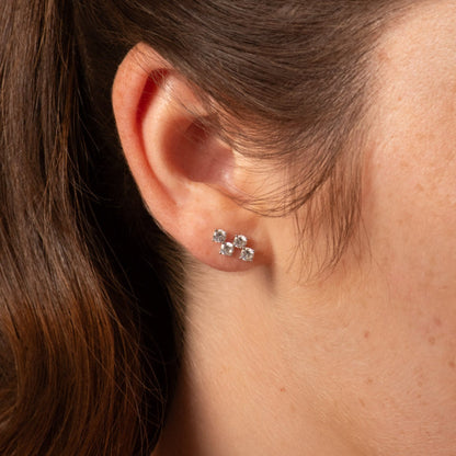 Silver diamond stud earrings with four clear stones in a clustered cross shape