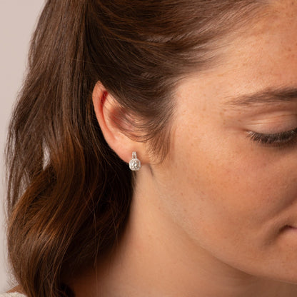 Teardrop diamond stud earrings with pavé halo on model ear