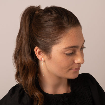 Silver crystal drop earrings with dangling teardrop stones on hoop backs