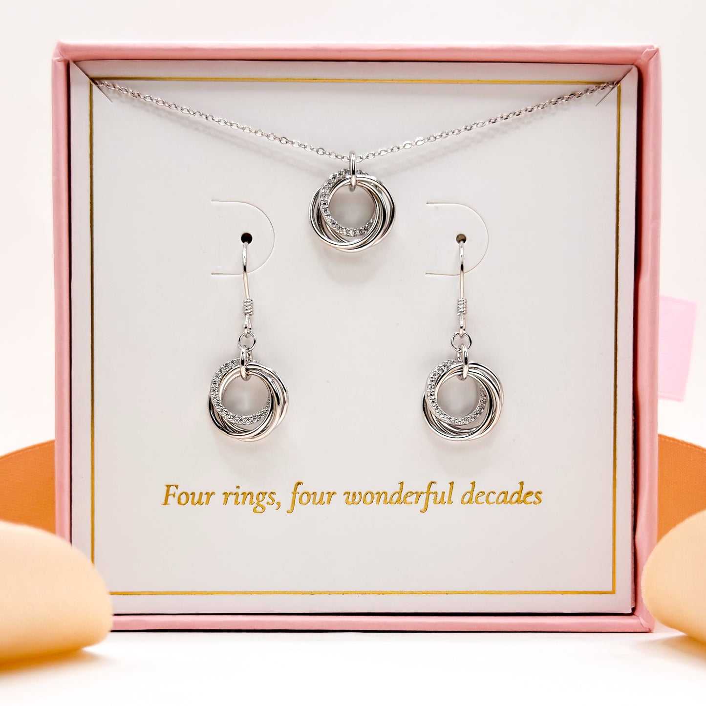 Silver ring pendant necklace and drop earrings displayed inside a pink jewellery gift box