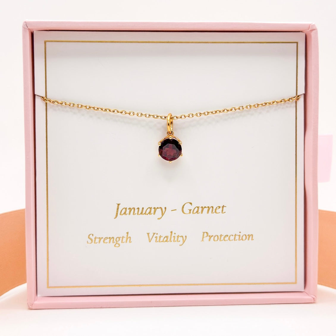 Gold necklace with small round red garnet pendant and fine chain