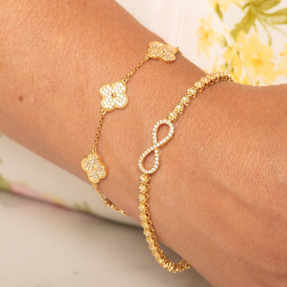 Gold and silver infinity charm bracelets together on wrist