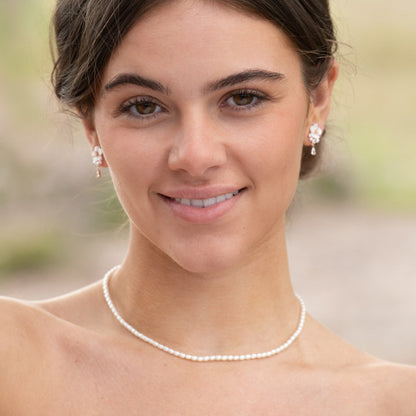 Pearl choker necklace with round white pearls, worn at the neckline