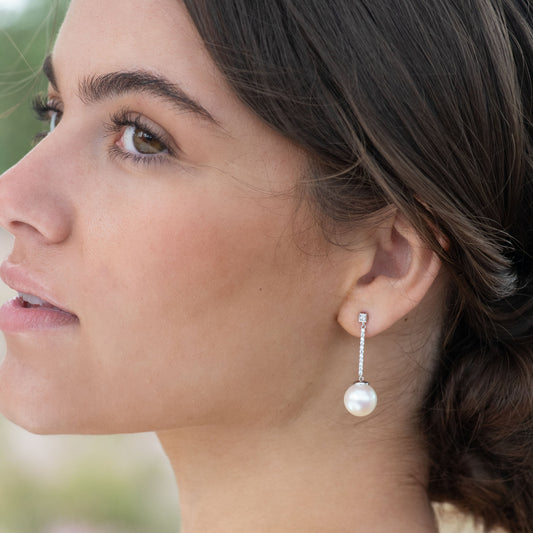 Close-up of a woman wearing a pearl earring with a blurred natural background