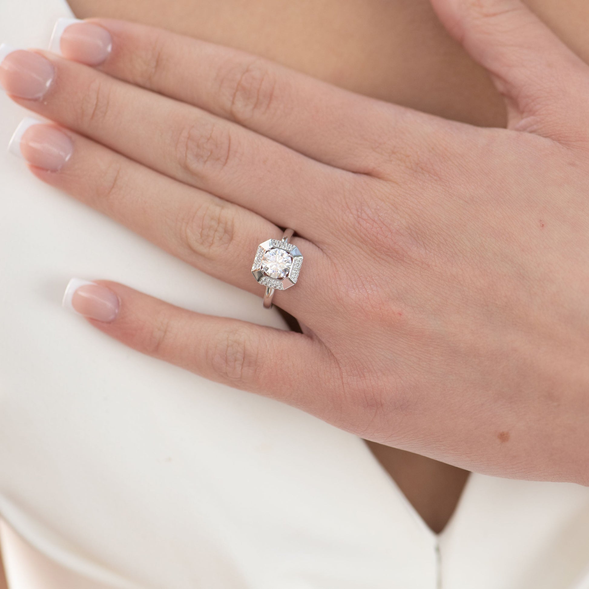 Close-up of a hand wearing a diamond ring on a white background