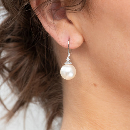 Pearl hook earring on ear with large round white pearl and jeweled top