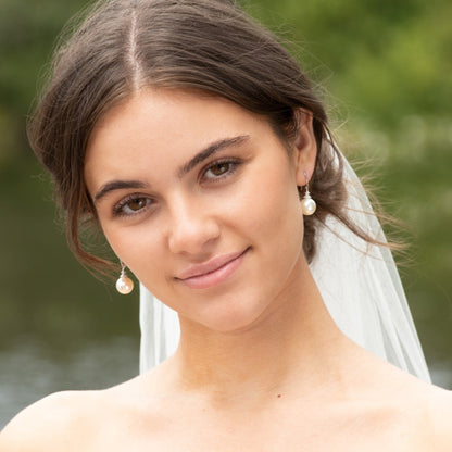 Pearl hook earring with large round pearl and jeweled cap on model with veil