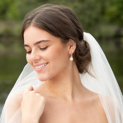 Pearl hook earrings with round white pearls and jeweled caps on model