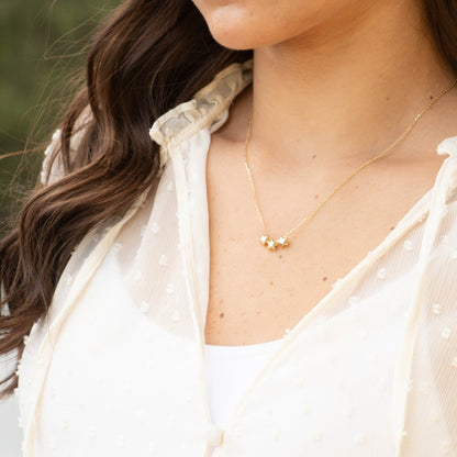Gold three-star necklace worn on neckline with three star pendants