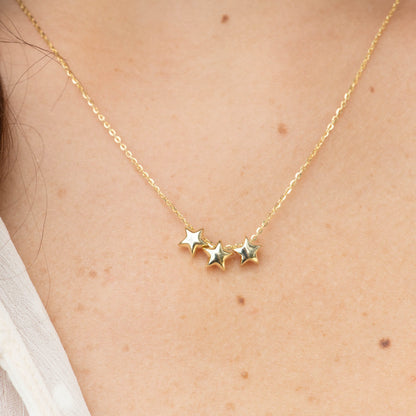 Gold three-star necklace close-up with three linked star charms