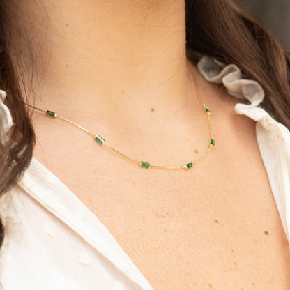 Gold-tone CZ baguette necklace with emerald green rectangular stones along the chain