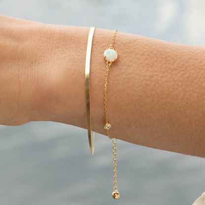 Gold bracelet with opal-like oval charm and small crystal bead links