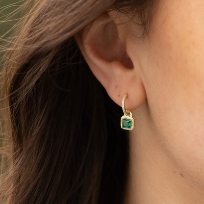 Close-up of gold-tone CZ drop earring with square green stone and pavé hoop