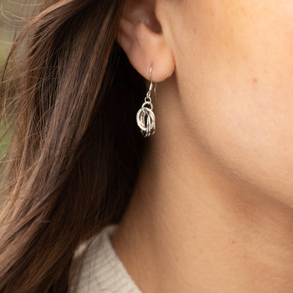 Silver drop earrings with triple linked ring pendant, close-up on ear