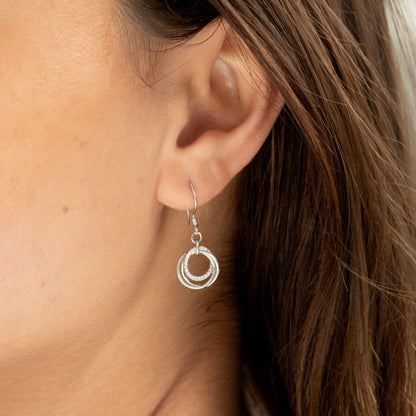 Silver drop earrings with three linked rings and small hanging circle charm