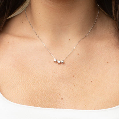 Silver three-star necklace worn on neckline with three small star charms