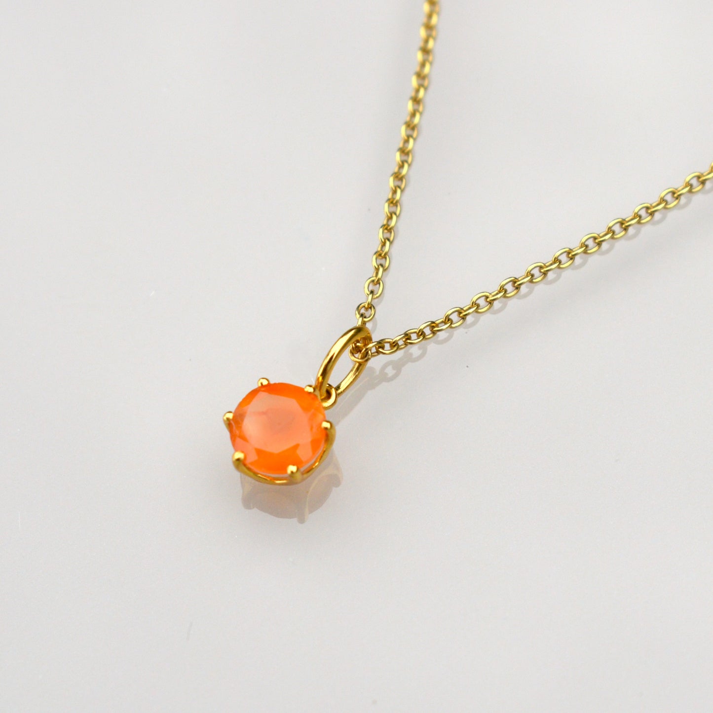 Gold necklace with oval orange gemstone pendant and linked chain