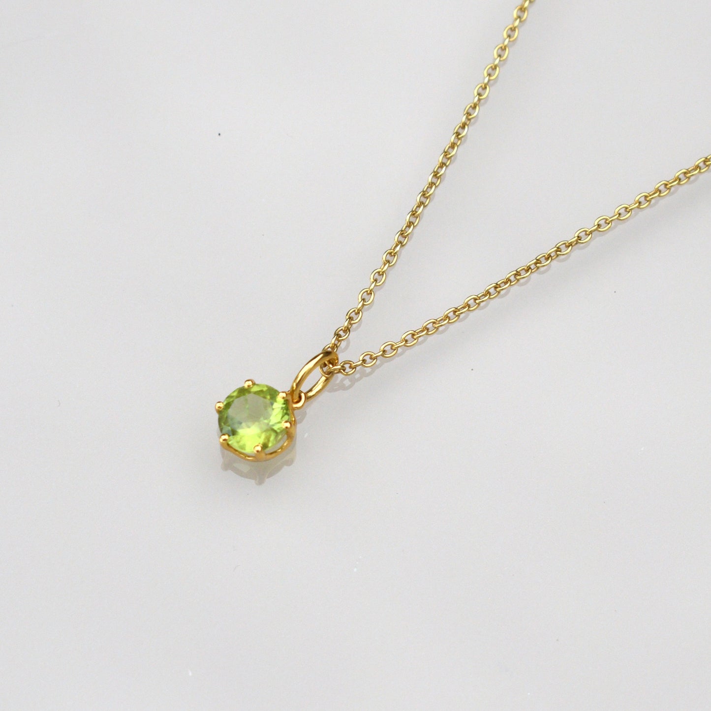 Peridot gemstone necklace with round green pendant and gold-tone chain