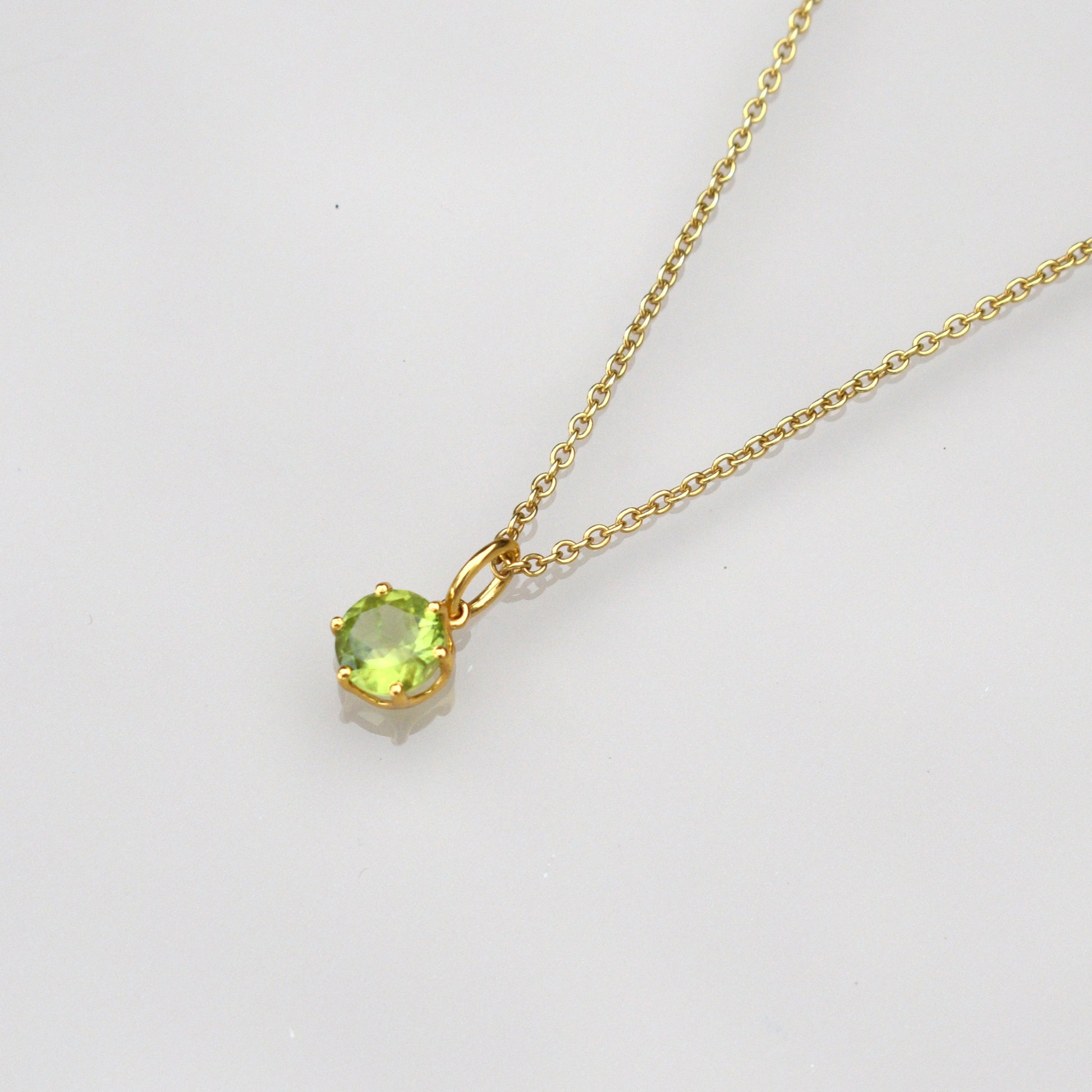 Peridot gemstone necklace with round green pendant and gold-tone chain