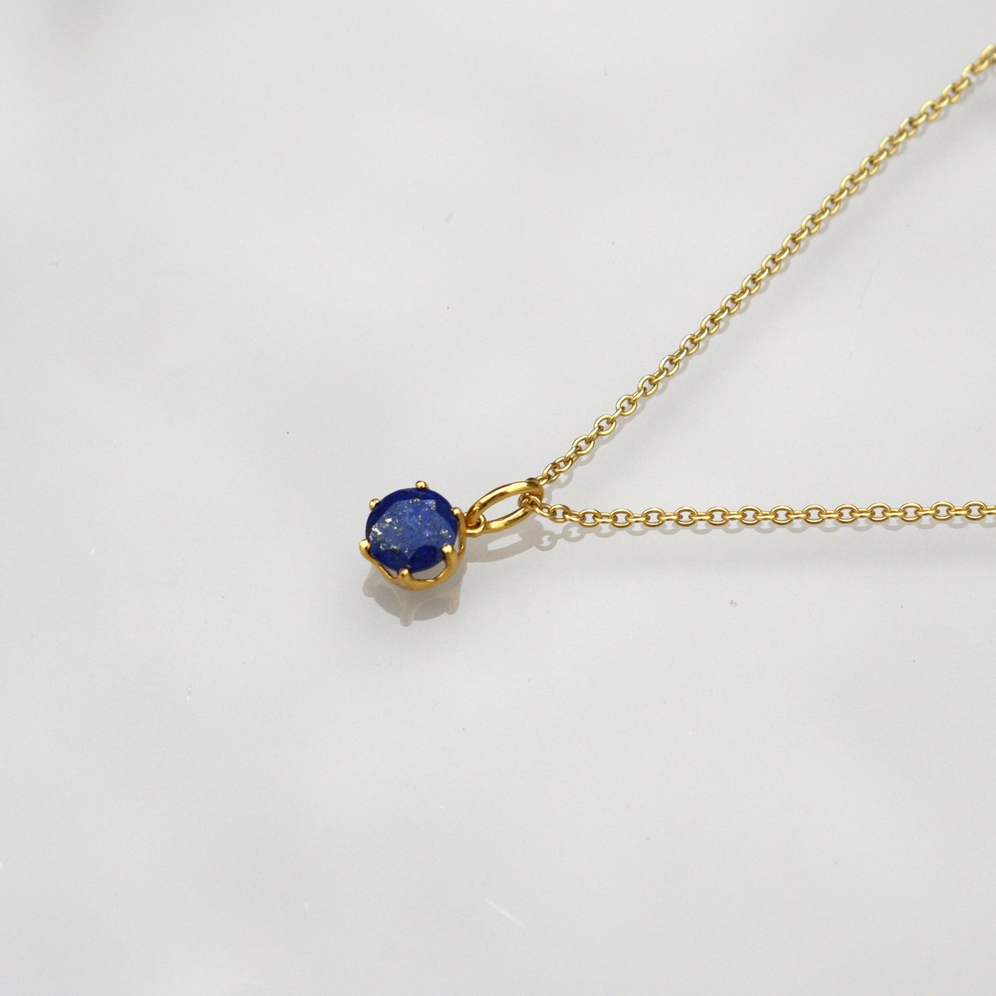 Gold-tone chain necklace with round blue lapis pendant and small bail detail