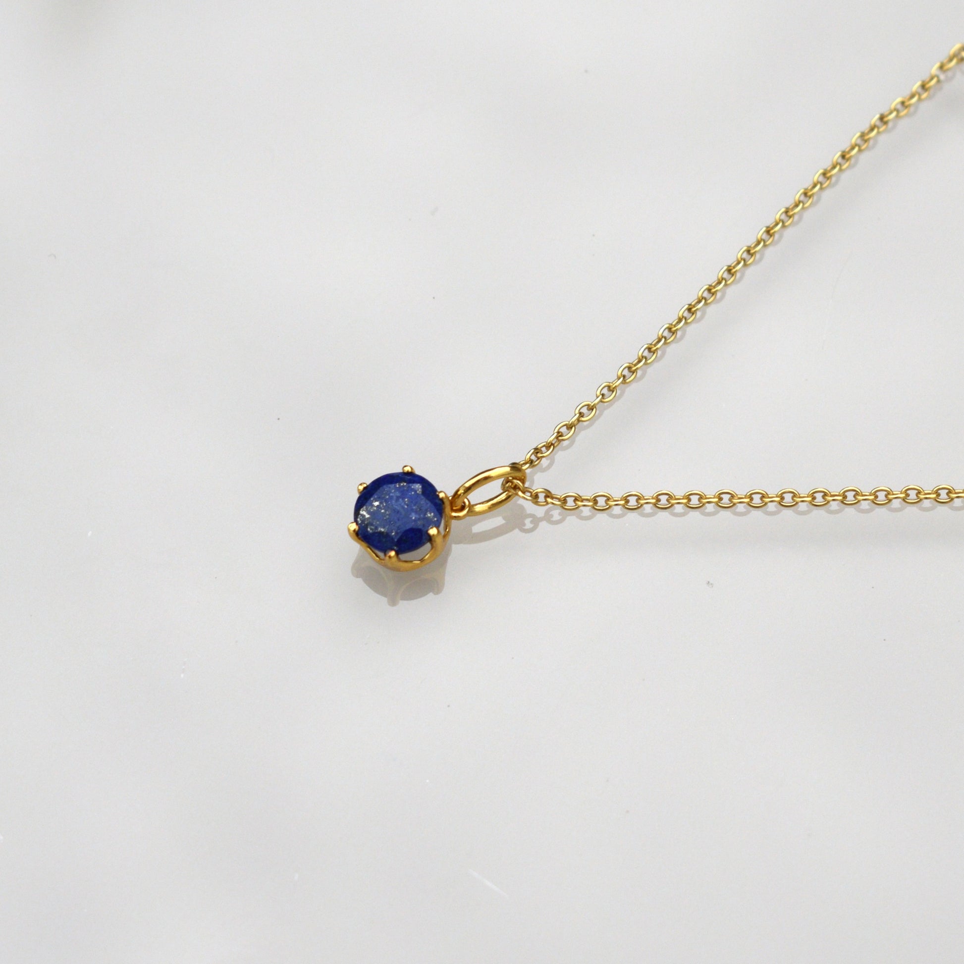 Gold-tone chain necklace with round blue lapis pendant and small bail detail