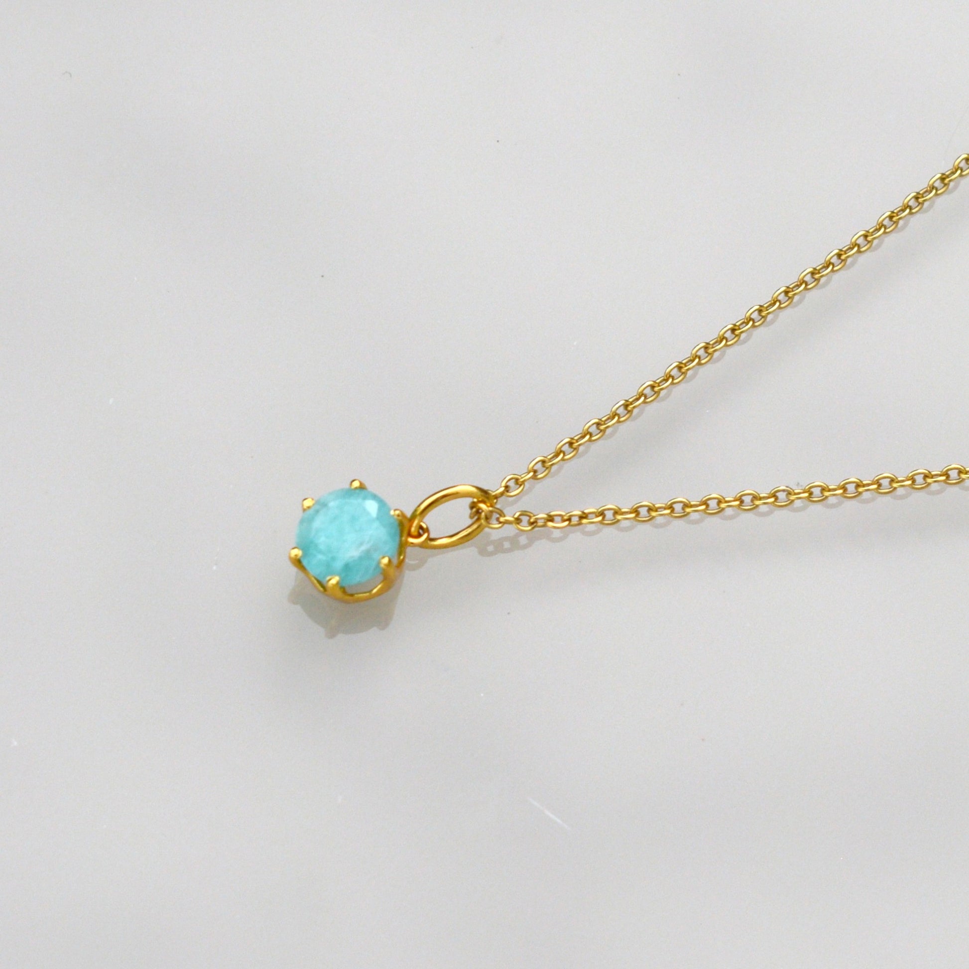 Gold necklace with round blue-green gemstone pendant on chain
