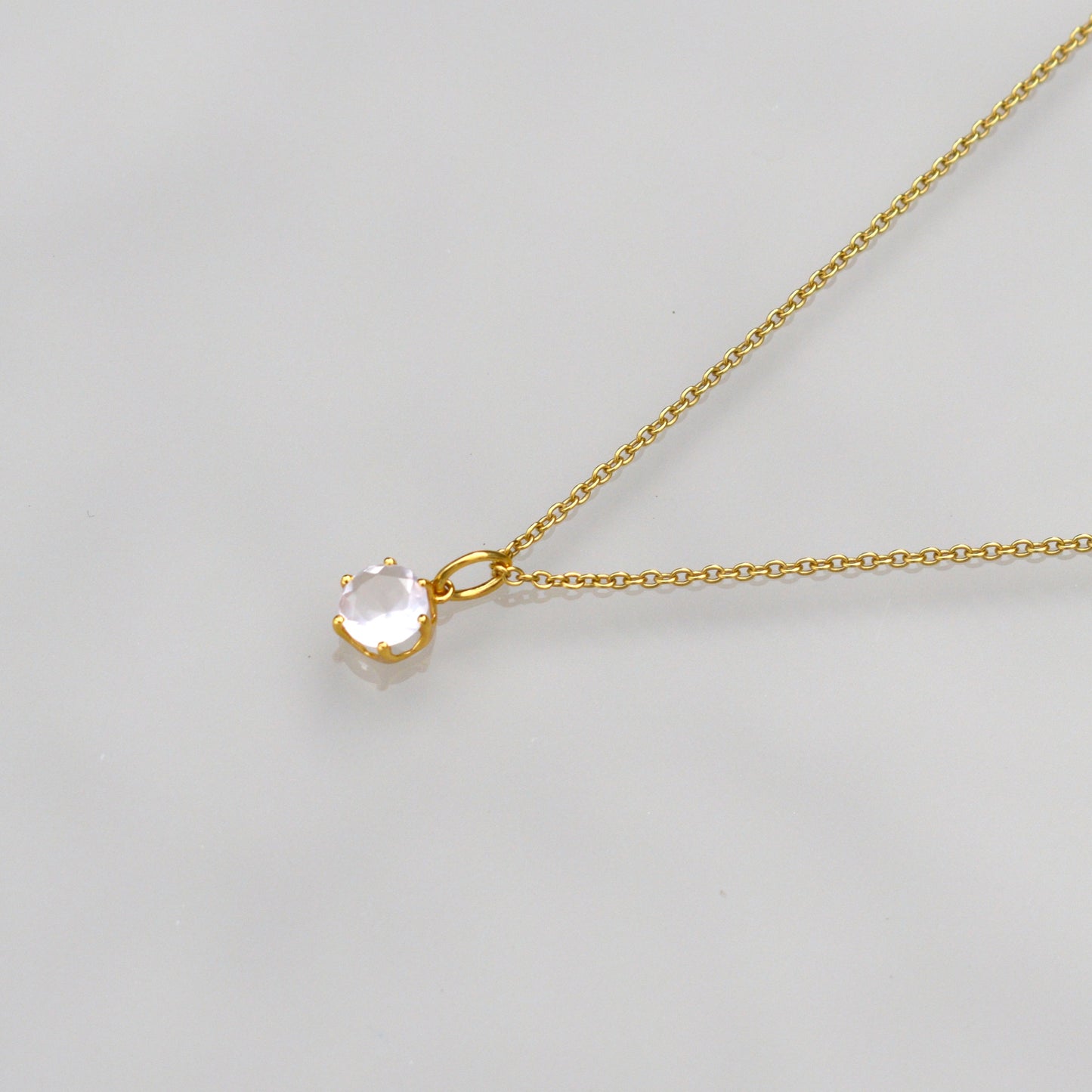 Gold-tone necklace with round rose quartz-style pendant on a fine chain