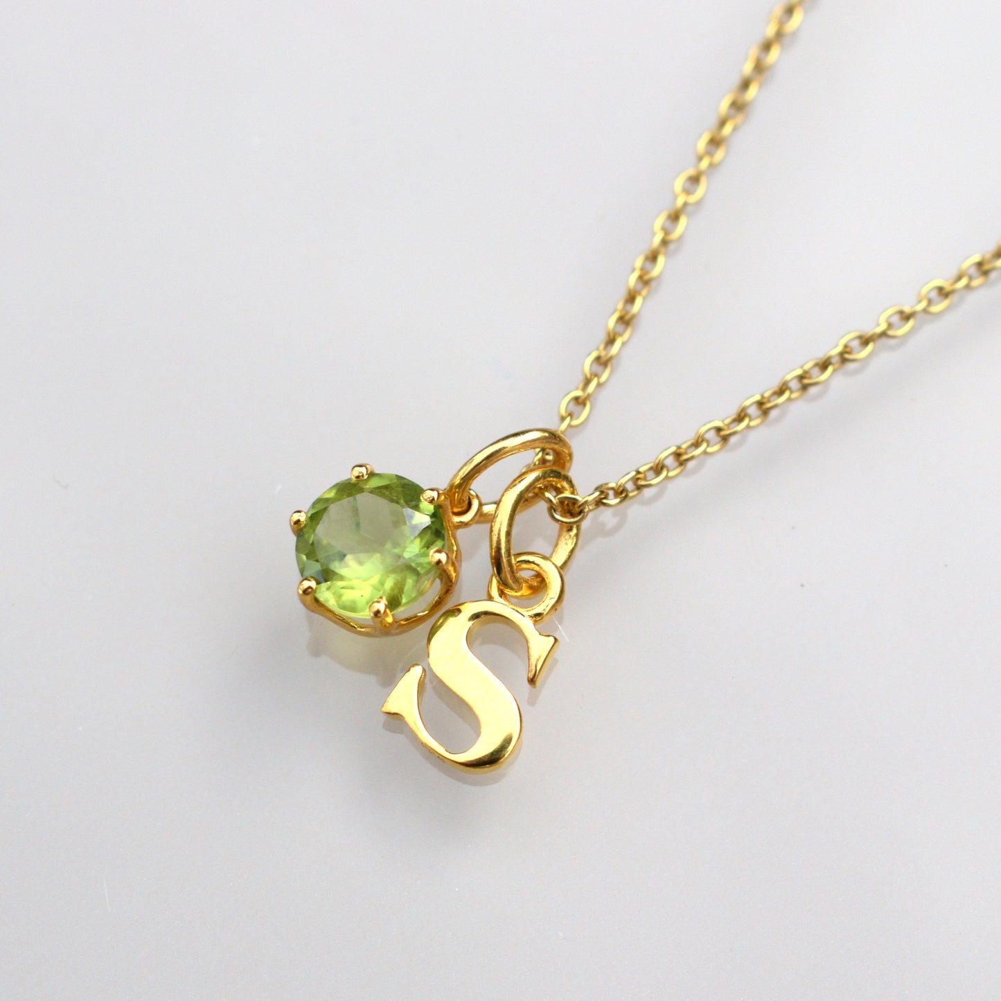 Peridot gemstone necklace with round green stone and heart charm on gold-tone chain