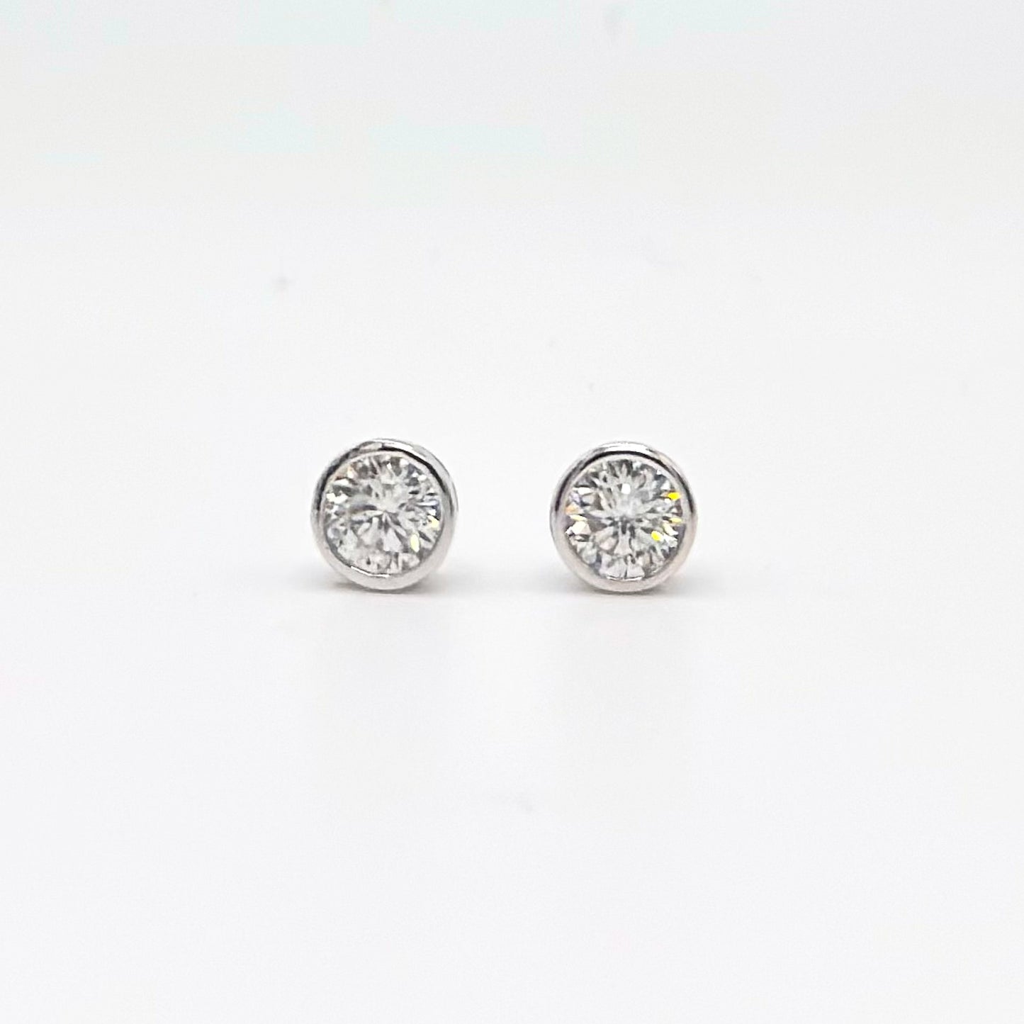 Round bezel-set moissanite stud earrings in silver-tone settings