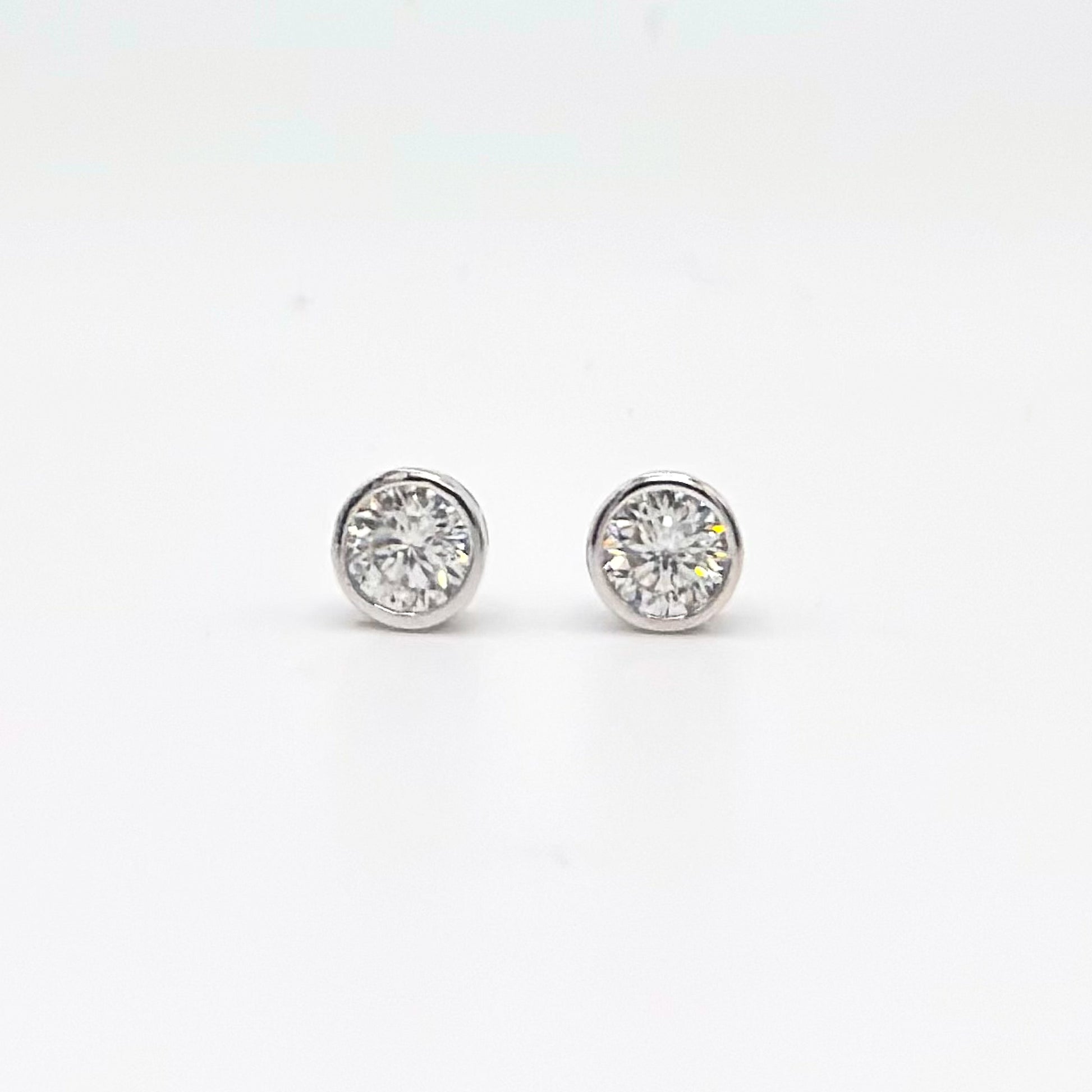 Round bezel-set moissanite stud earrings in silver-tone settings