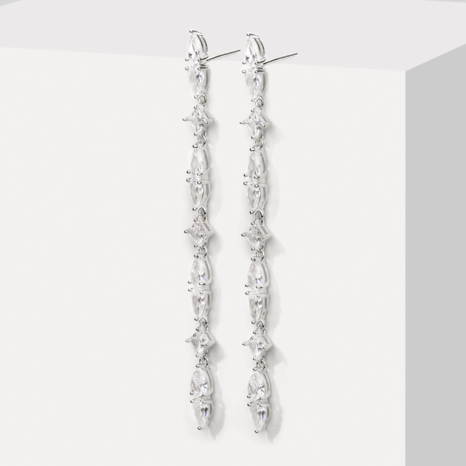 Silver earrings with clear stones on a white background