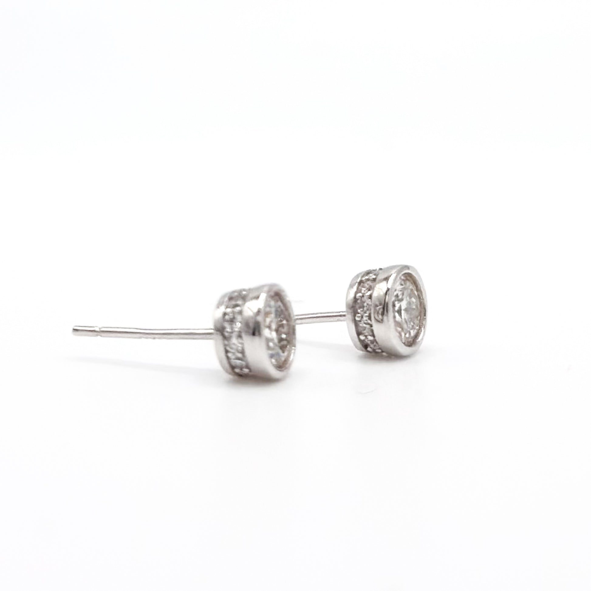 Round moissanite stud earrings with visible posts and bezel-set stones, silver-tone